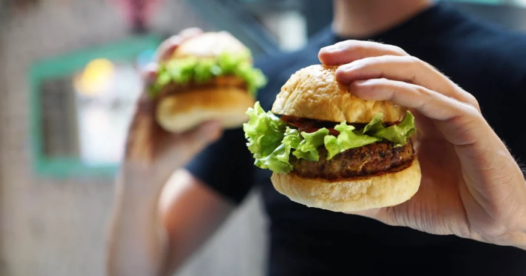 Persona che mangia un panino di un fastfood