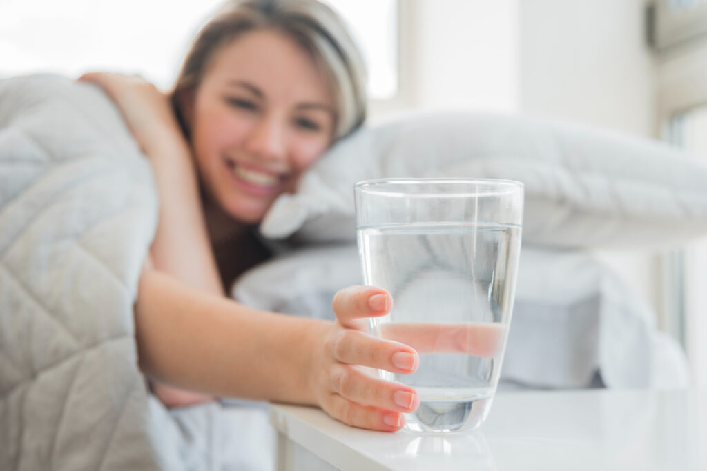 Persona che beve un bicchiere d'acqua al mattino in cucina