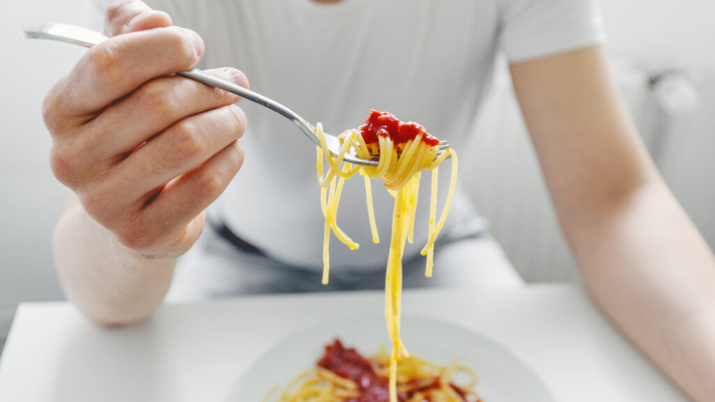 Persona seduta a tavola che mangia lentamente in un ambiente domestico luminoso